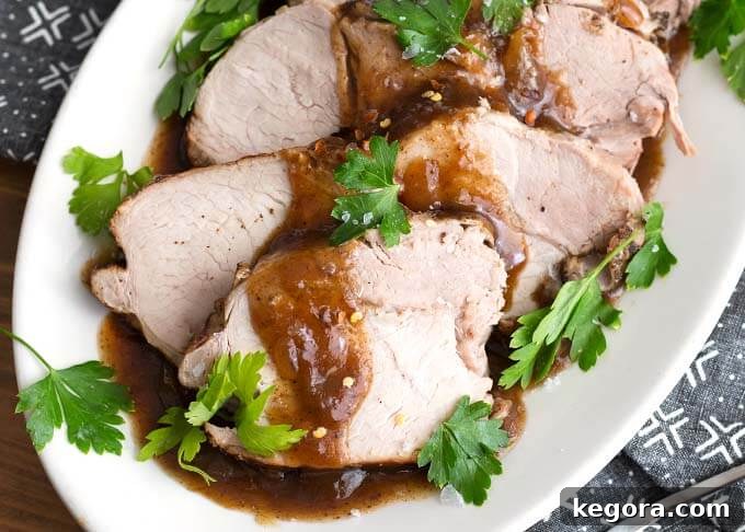Balsamic Glazed Instant Pot Pork Loin 3 Closeup of Sliced Balsamic Pork Loin Roast with fresh parsley on a white oblong platter