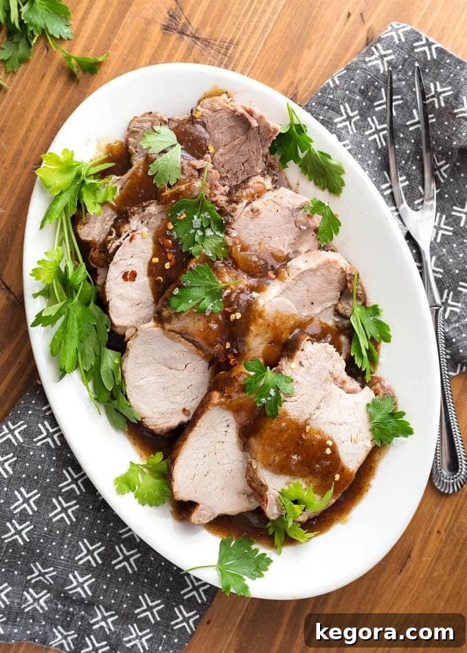 Balsamic Glazed Instant Pot Pork Loin 4 Top view of Sliced Balsamic Pork Loin Roast with fresh parsley on a white oblong platter