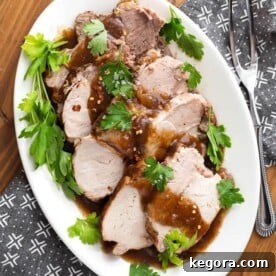 Top view of Sliced Balsamic Pork Loin Roast with fresh parsley on a white oblong platter