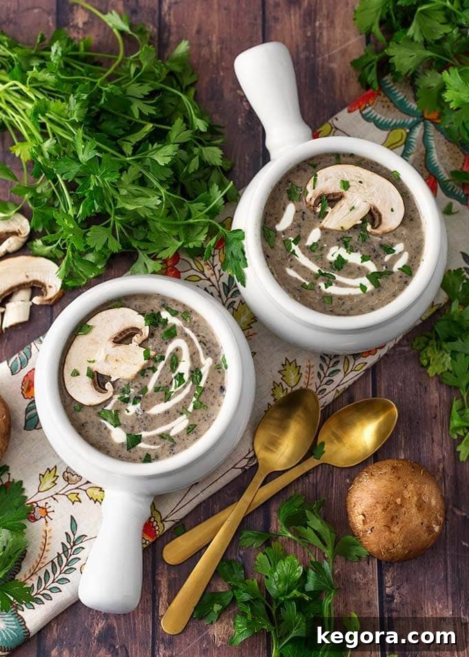 15 Delicious Instant Pot Soups 14 Two white bowls of elegant Instant Pot Mushroom Soup, garnished with fresh parsley and golden spoons, presented on a rustic wooden background, emphasizing its rich and earthy flavors.