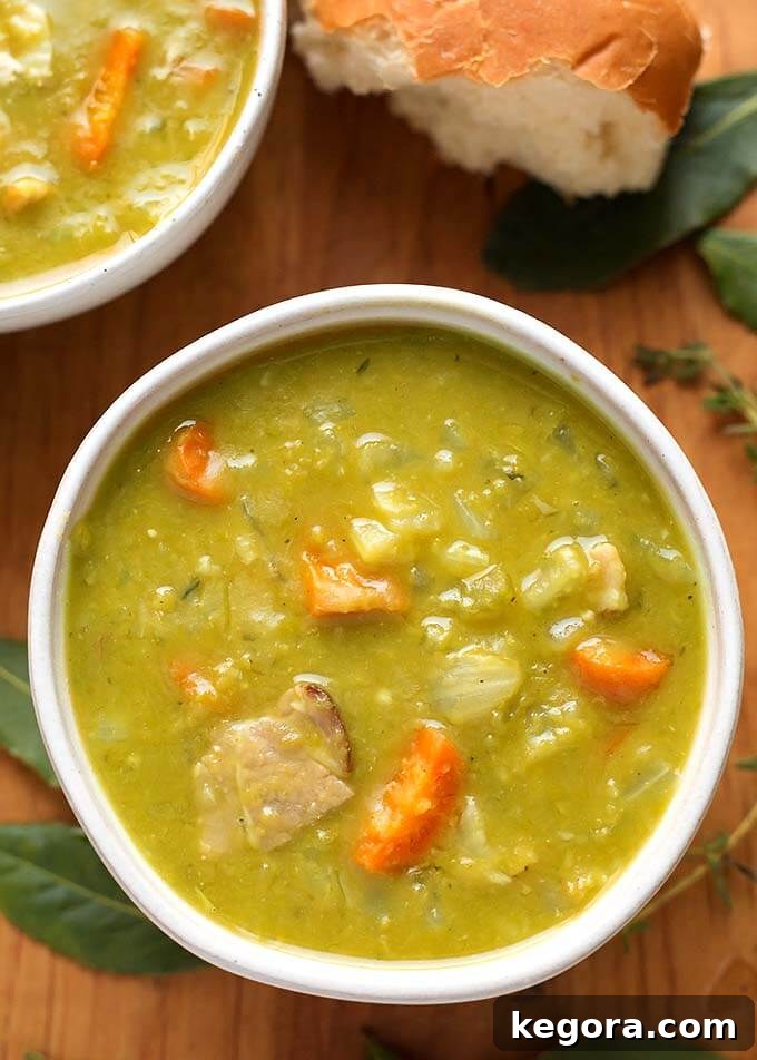 15 Delicious Instant Pot Soups 15 A comforting bowl of Instant Pot Split Pea Soup on a wooden board, showcasing its thick, hearty texture and savory ham pieces, a classic favorite from childhood.