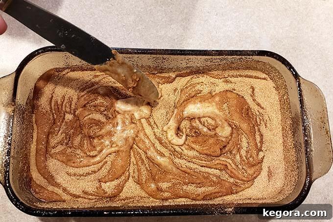 whirling cinnamon and sugar with a knife in a glass pan of unbaked cinnamon bread