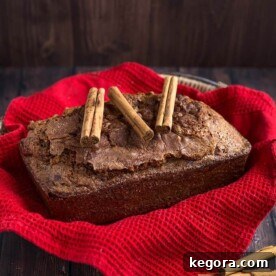 Whole loaf of Nana's Easy Cinnamon Bread topped with three cinnamon sticks all on top of a basket lined with a red napkin