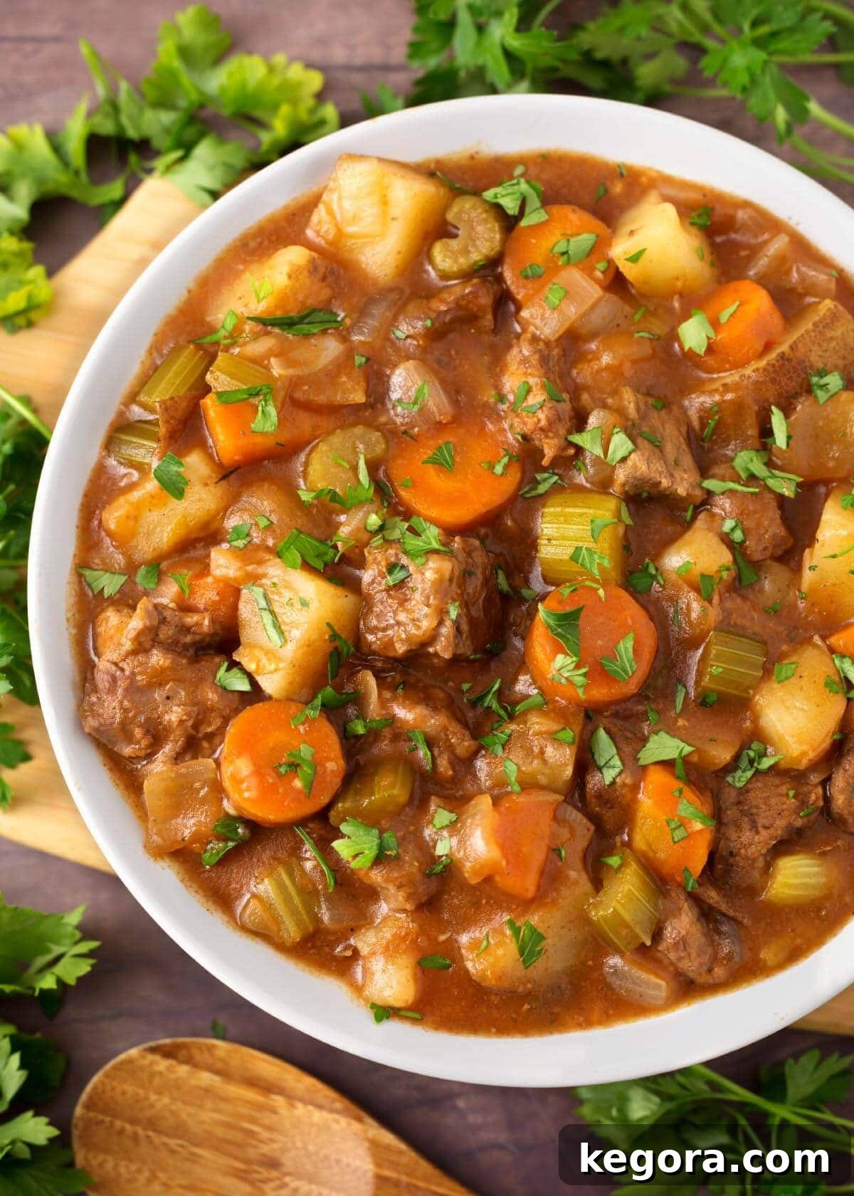No-Fuss Slow Cooker Beef Stew 2 Beef Stew in a white bowl on a wooden board next to fresh parsley