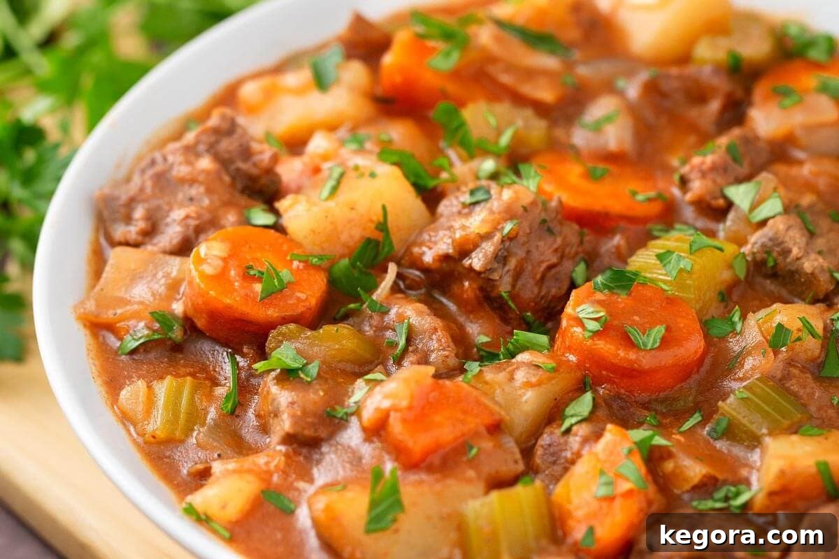 No-Fuss Slow Cooker Beef Stew 3 Beef Stew in a white bowl on a wooden board next to fresh parsley