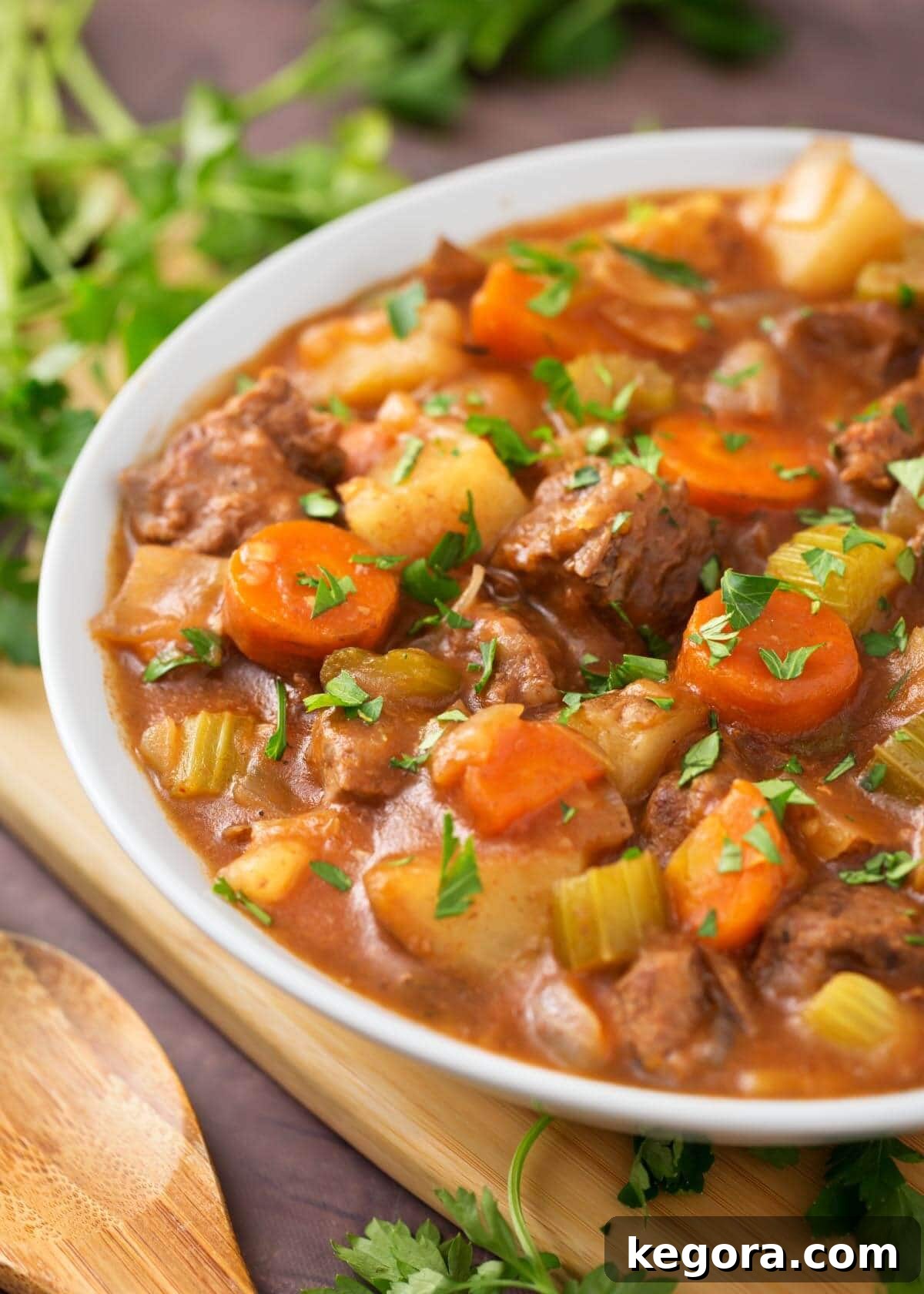 No-Fuss Slow Cooker Beef Stew 4 Beef Stew in a white bowl on a wooden board next to fresh parsley