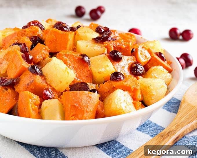 Instant Pot Sweet Potato Cranberry Delight 3 Side view of Instant Pot Sweet Potato Cranberry Casserole in a white bowl on a white and blue napkin next to a wooden spoon