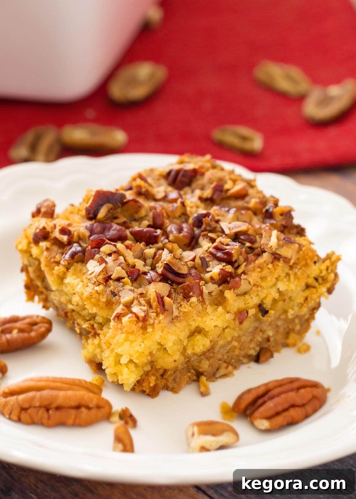 Autumn Spiced Pumpkin Crumble 2 Slice of Pumpkin Pie Dump Cake on a white plate with pecan halves and a spoon of whipped cream