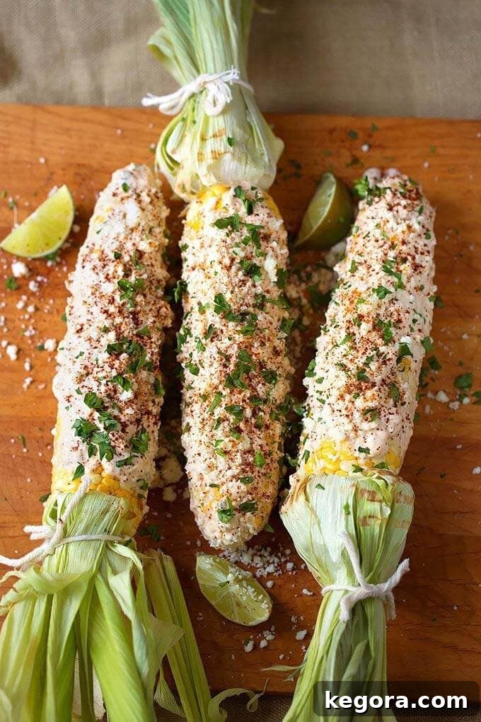 Authentic Mexican Elotes 2 Three perfectly grilled Mexican Street Corn (Elotes) on a rustic wooden board, garnished with cilantro.