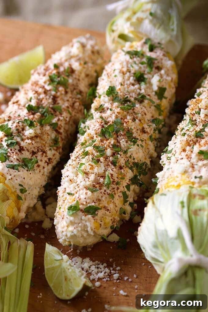 Authentic Mexican Elotes 3 Mexican Street Corn (Elotes) artfully arranged on a wooden board, with fresh lime wedges for serving.