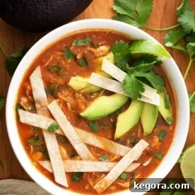 A vibrant bowl of Instant Pot Chicken Tortilla Soup, generously topped with crispy tortilla strips, creamy avocado slices, and fresh cilantro, promising a delightful blend of Mexican flavors.
