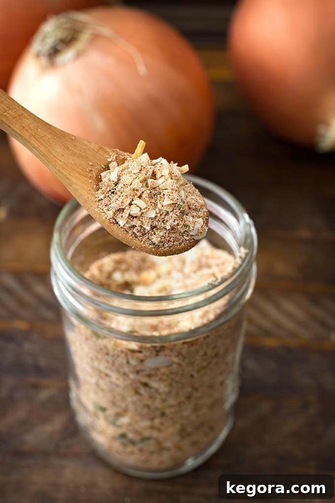 Closeup of wooden spoon scooping up Homemade Onion Soup Mix from a small glass jar