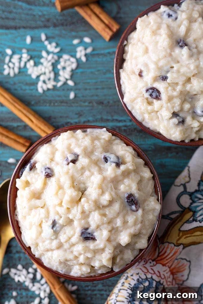 Two brown bowls of Creamy Instant Pot Rice Pudding next to cinnamon sticks on a turquoise background