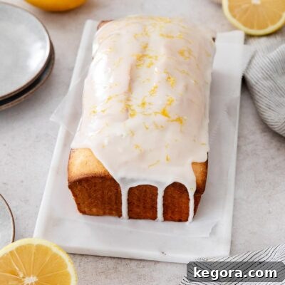 Sliced gluten-free lemon loaf on a marble serving tray with lemons around it.