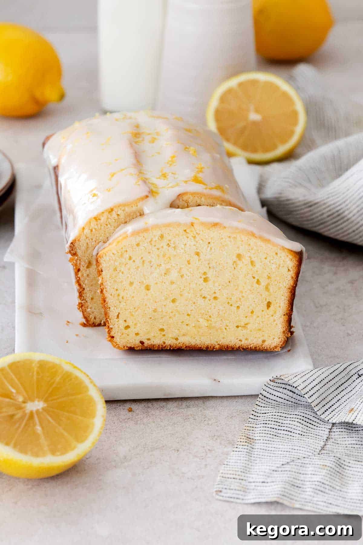 A sliced gluten-free lemon loaf resting on a marble serving tray, garnished with fresh lemon slices.