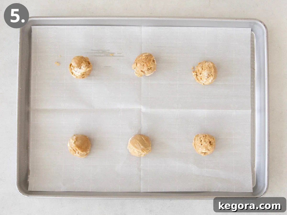 Gluten-Free Fluffernutter Cookies: Peanut Butter and Marshmallow 6 A baking sheet lined with parchment paper holds six evenly spaced scoops of cookie dough, arranged in two rows of three. A gray number 5 is in the top left corner.