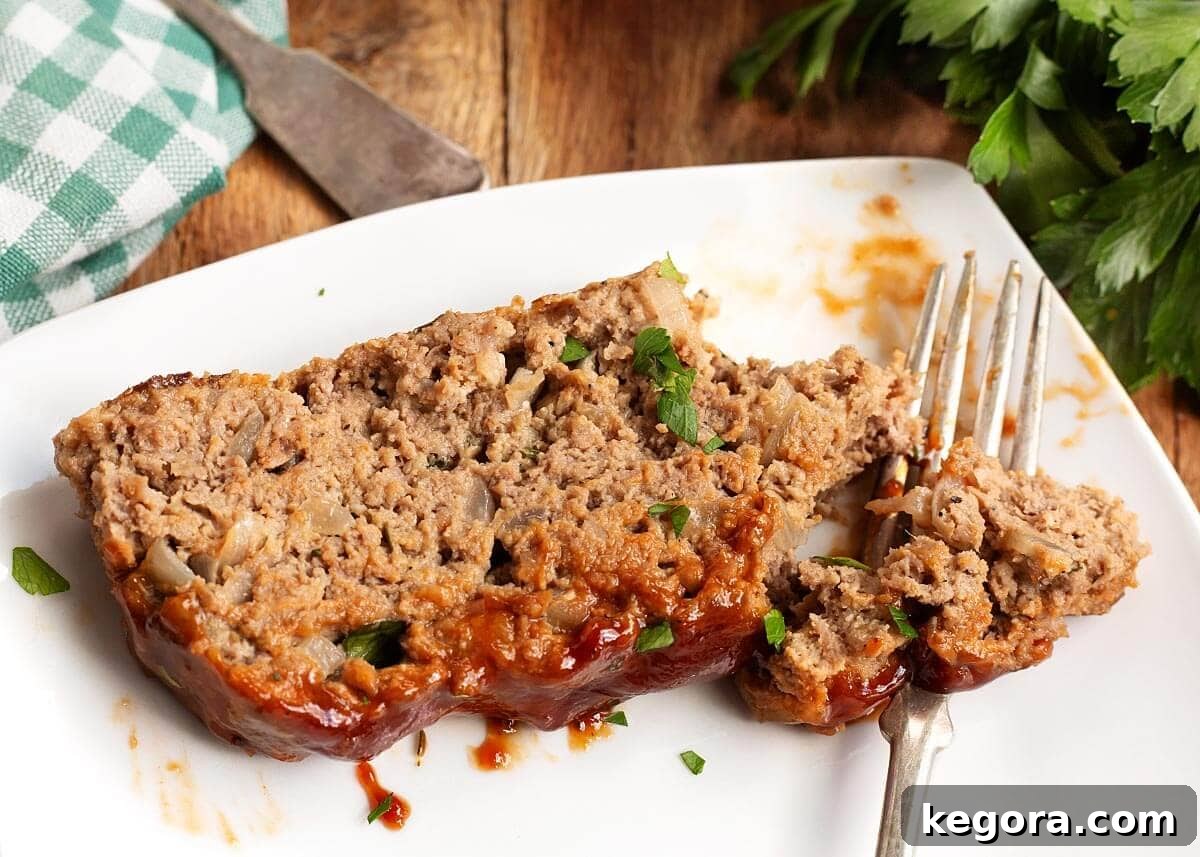 How to Make Classic Moist Meatloaf with Glazed Topping 4 Slice of meatloaf on a white plate with a fork