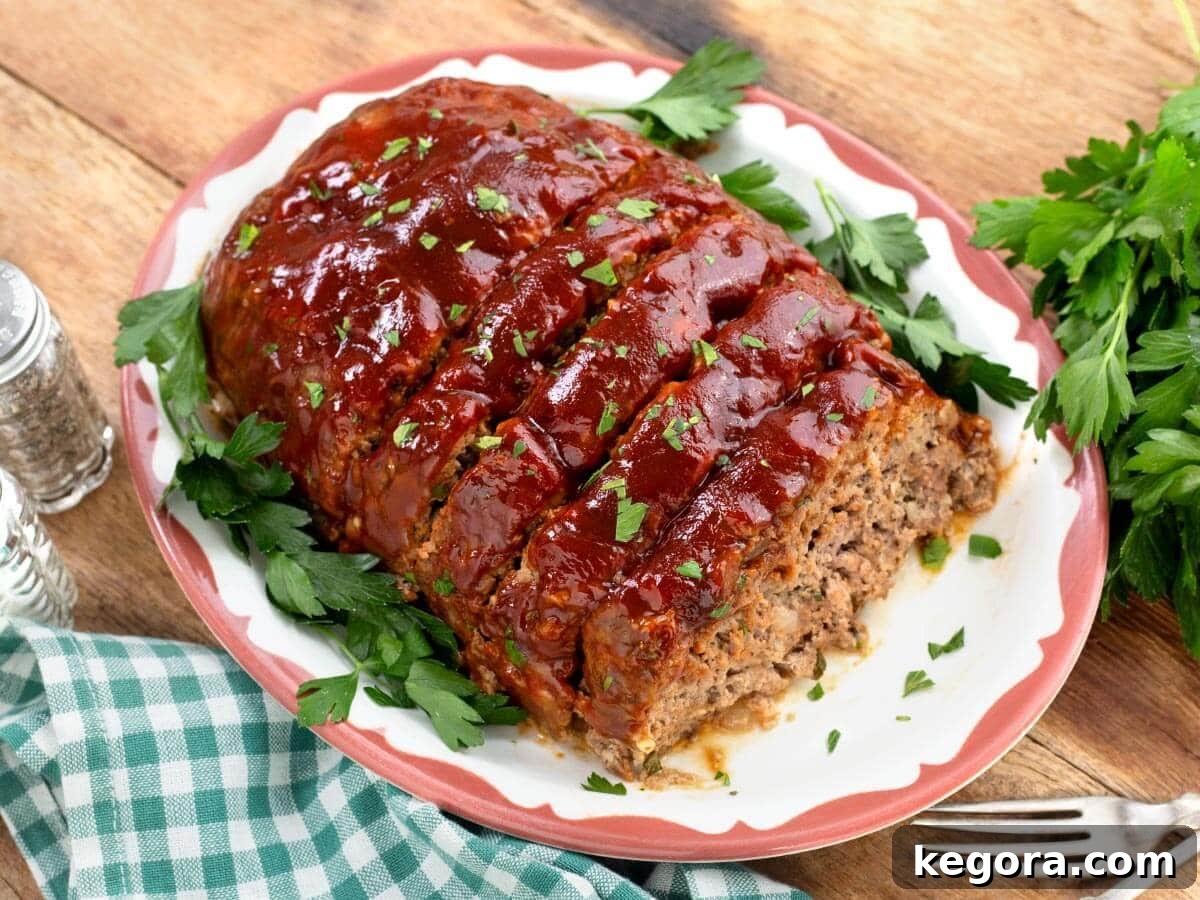 How to Make Classic Moist Meatloaf with Glazed Topping 9 Partially sliced cooked meatloaf on a white platter