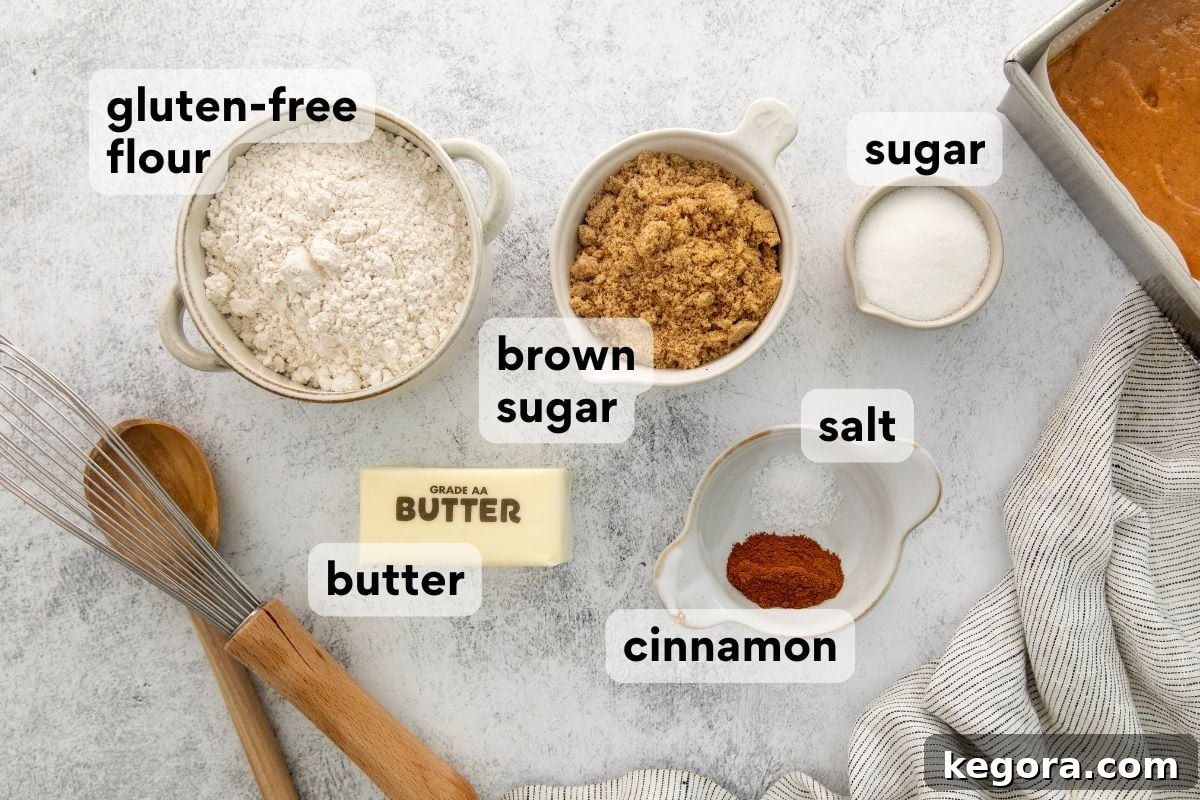 Gluten-Free Pumpkin Crumb Cake Recipe 3 Various baking ingredients on a table, including labeled bowls of gluten-free flour, brown sugar, sugar, salt, cinnamon, and a stick of butter, with a whisk and wooden spoon nearby.