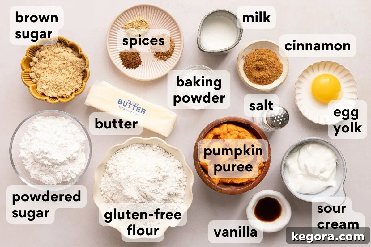 Flaky Gluten-Free Pumpkin Scones Recipe 3 Labeled ingredients on a table for baking: brown sugar, spices, baking powder, butter, gluten-free flour, powdered sugar, milk, cinnamon, salt, egg yolk, pumpkin puree, sour cream, and vanilla.