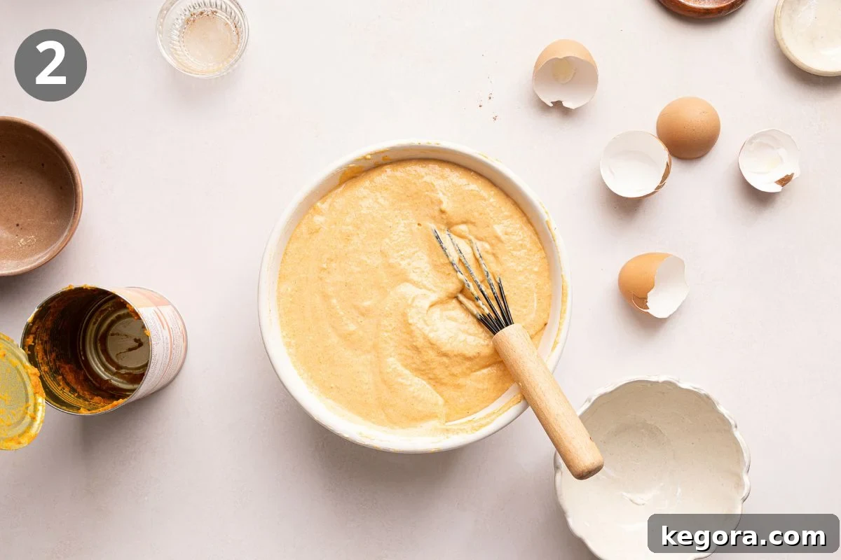 A mixing bowl with batter and a whisk, surrounded by eggshells, an empty can, small bowls, and a glass. The number 2 is in a gray circle in the top left corner.